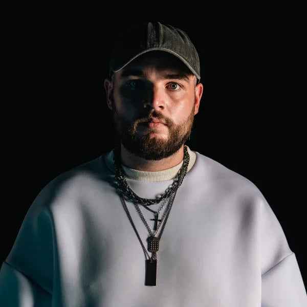 Man in streetwear with cap, layered chains and white sweatshirt, hard techno style